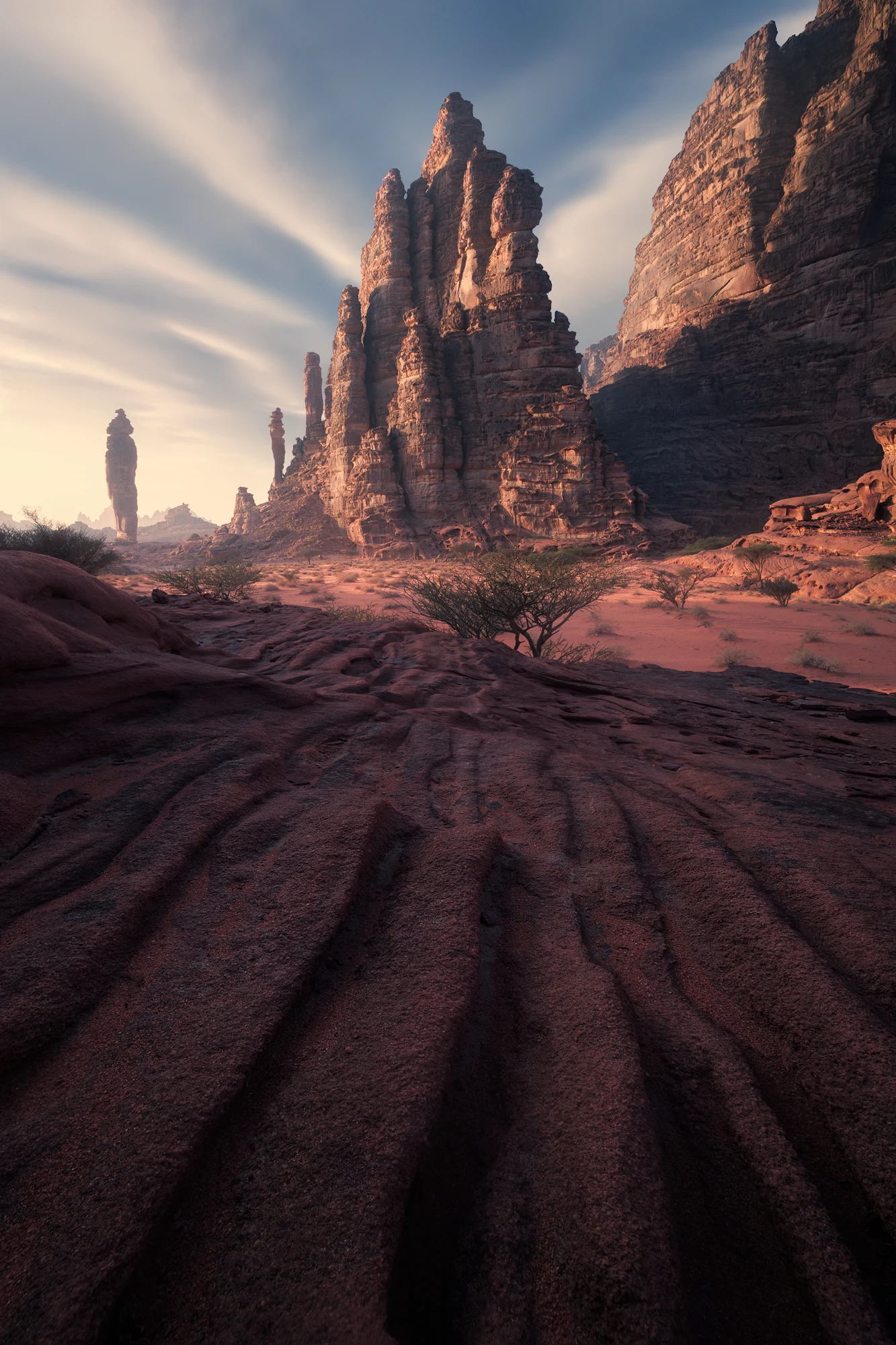 Towering sandstone monoliths in Tabuk, Saudi Arabia at sunrise with dramatic clouds and desert textures
